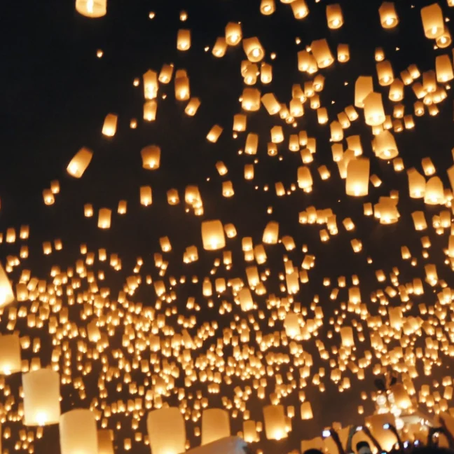 Photo of thousands of Khom Loy (lanterns) floating into the air during Yee Peng Ceremony at Mae Jo University in Chiang Mai Thailand